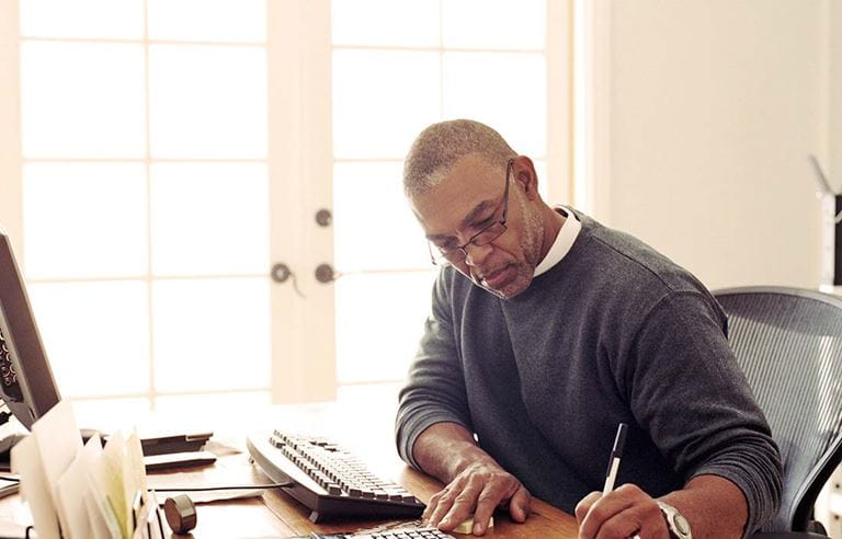 Man sitting at a desk, writing something down