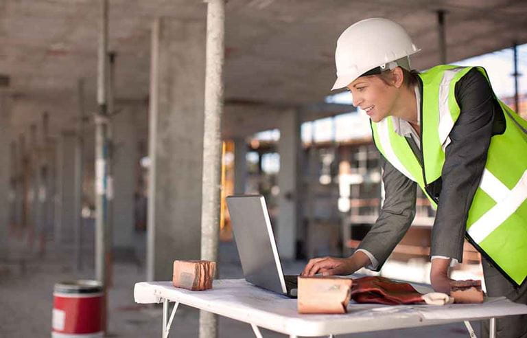 Construction foreman using a laptop computer at a construction site.