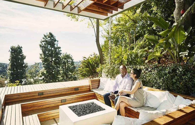 A couple smiling and holding hands in an outdoor area. 