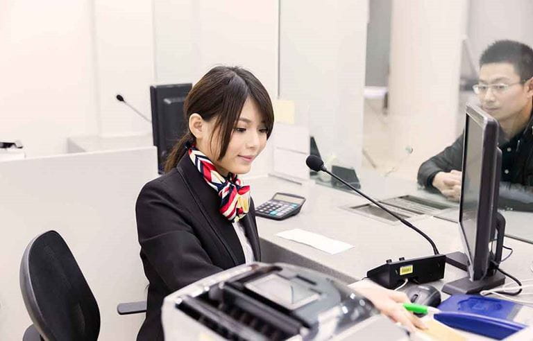 Female administrative worker working at a front desk helping a customer.