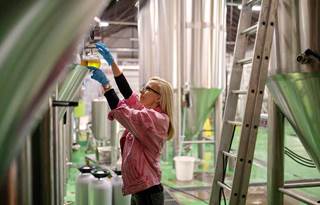 A woman working in a factory nearby metal silos.