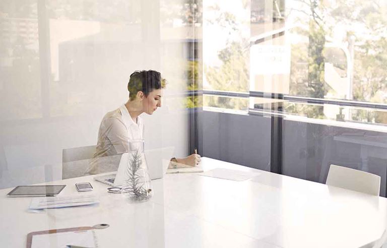 Woman in an office writing on a notepad