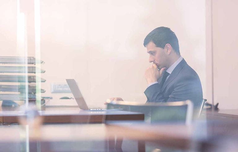 Businessman using laptop computer at desk.