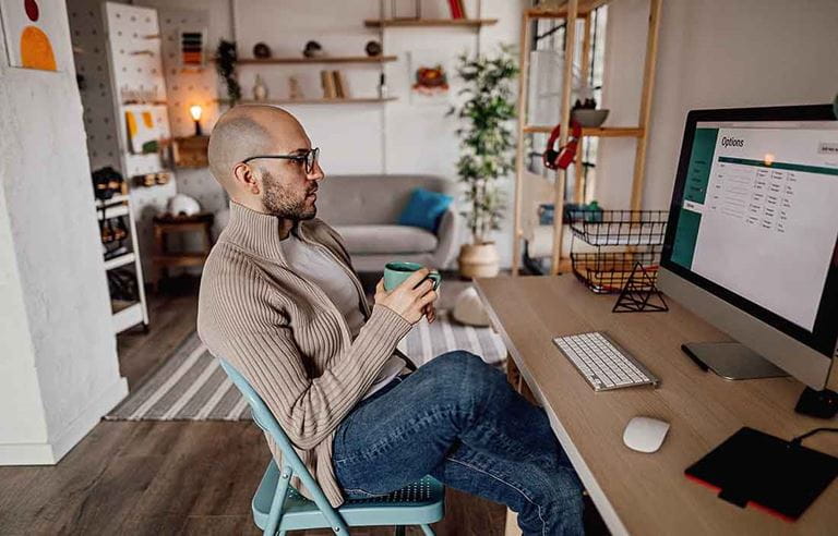 Businessperson having a cup of coffee while viewing their monitor screen.