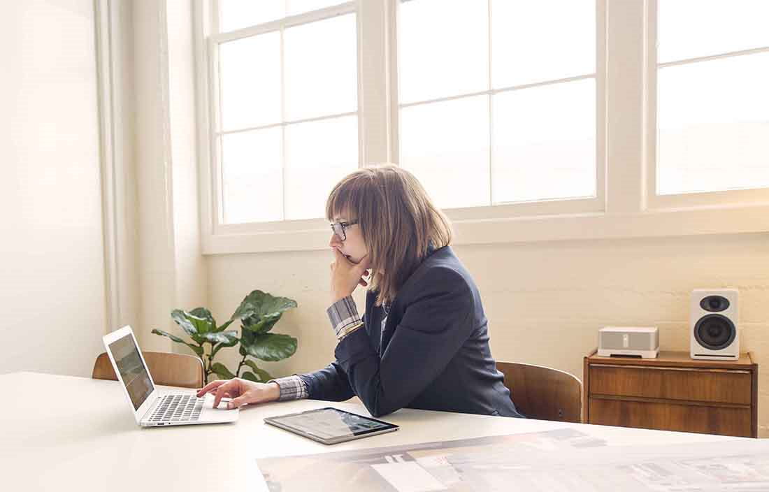 Businessperson using laptop in home office setting.