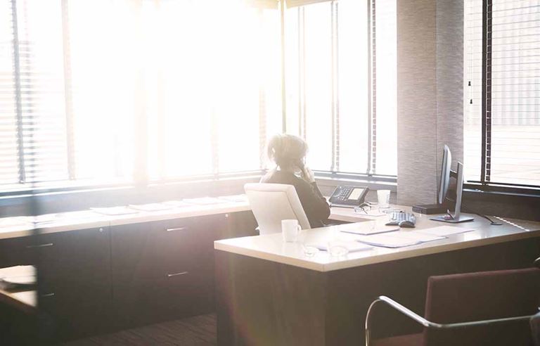 Businesswoman sitting at her office desk using an office phone.