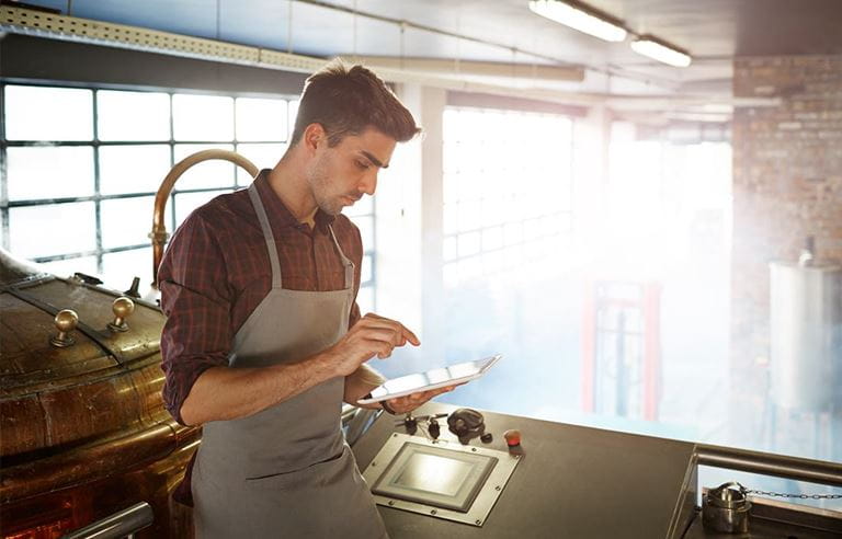 Worker wearing an apron using a handheld tablet computer.