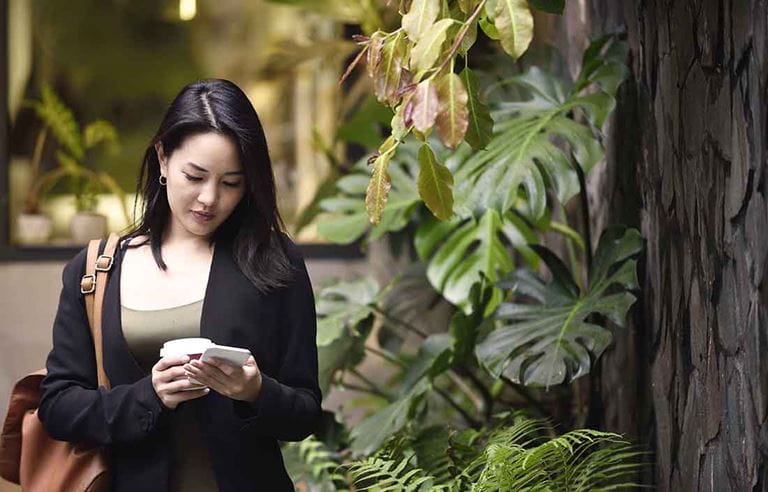 Business professional in nice dress clothes checking their phone in an outdoor patio area. 