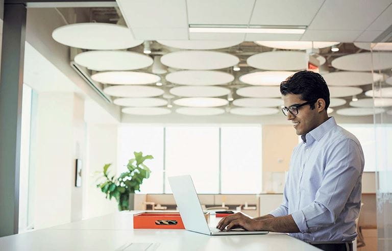 Business professional using a standing desk with a laptop computer.