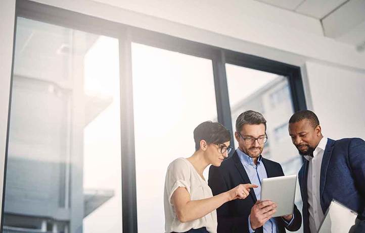 Three business professionals reviewing the NAPIS study on a tablet.