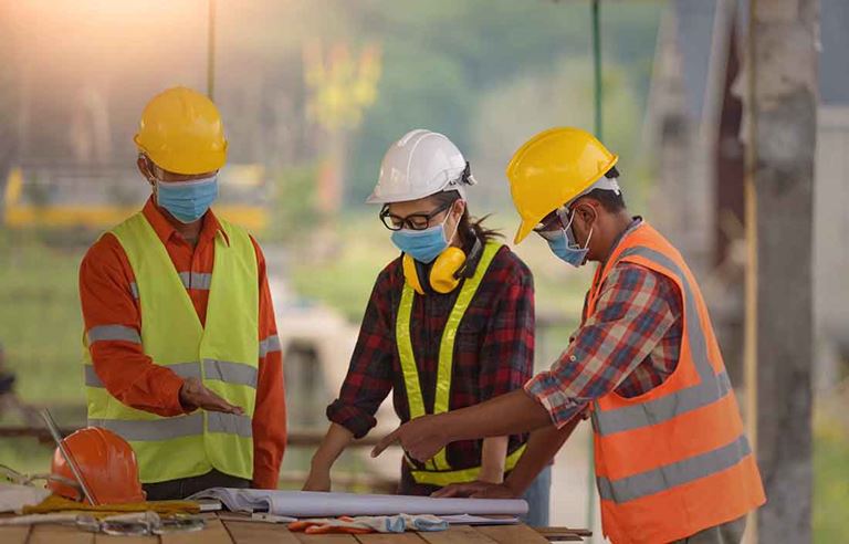 Construction workers wearing protective facemasks.