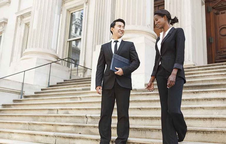 Two business professionals walking down concrete steps.