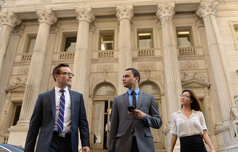 Business professionals walking outside a courthouse.