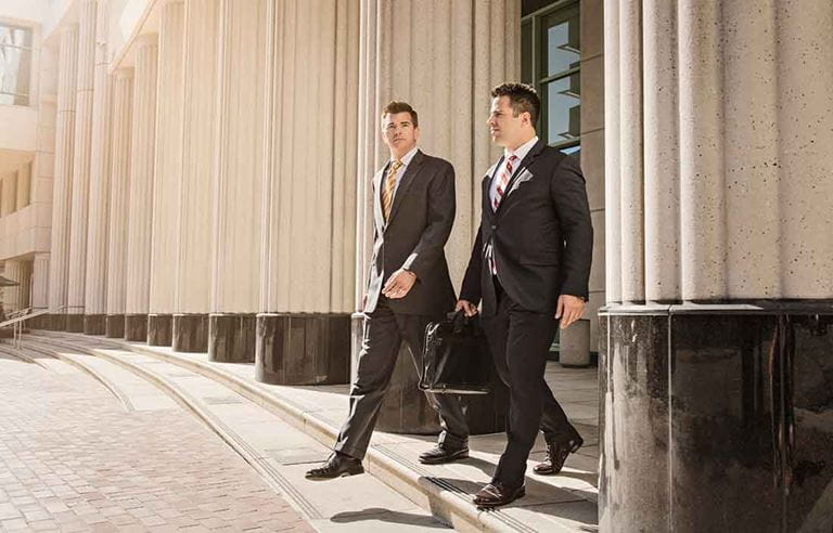 Photo of two business professionals walking out of a building.