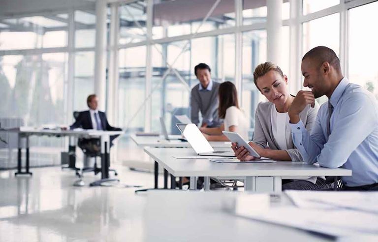 Photo of business people sitting by desk in a very modern office building.