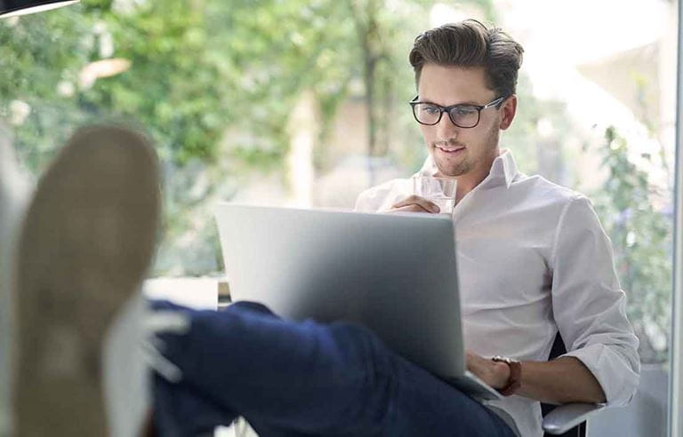 Young professional sitting in a chair using a laptop computer.