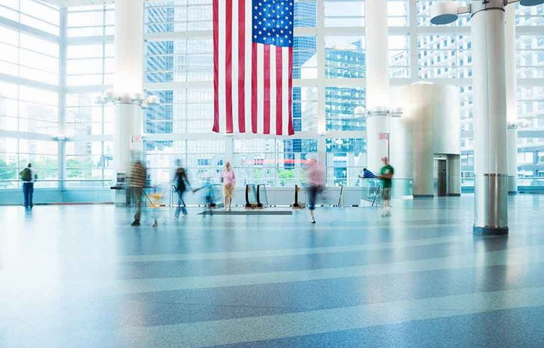 Photo of an American flag hanging in the interior lobby of a building.