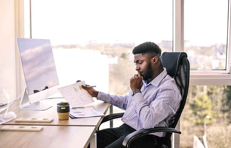 Business professional sitting at their desk reading paper documents.