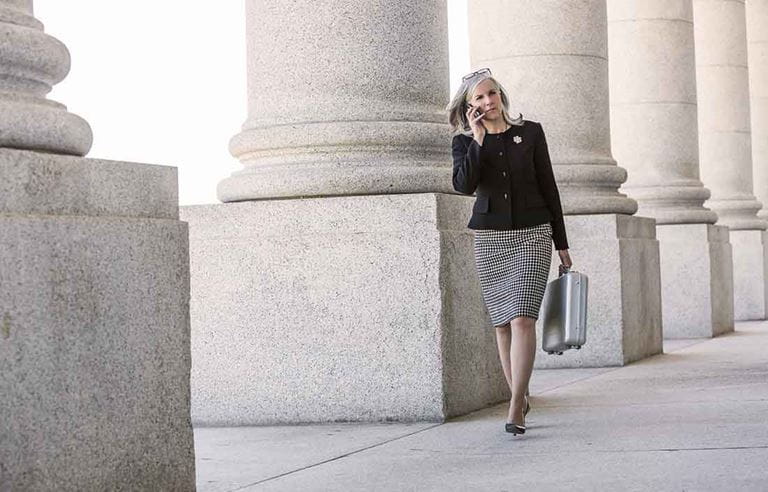 A business professional walking past concrete columns.