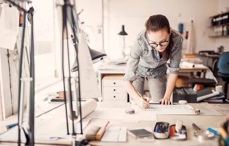 Business professional leaning down over a desk looking at paperwork.