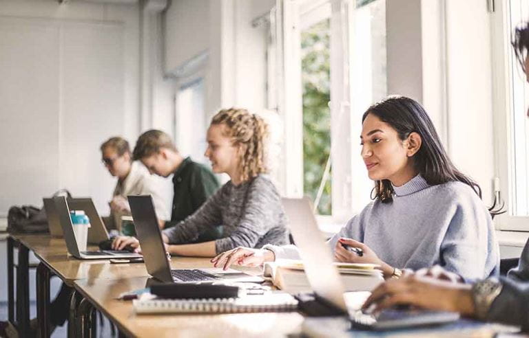 Business professionals sitting at their desks working on laptop computers.