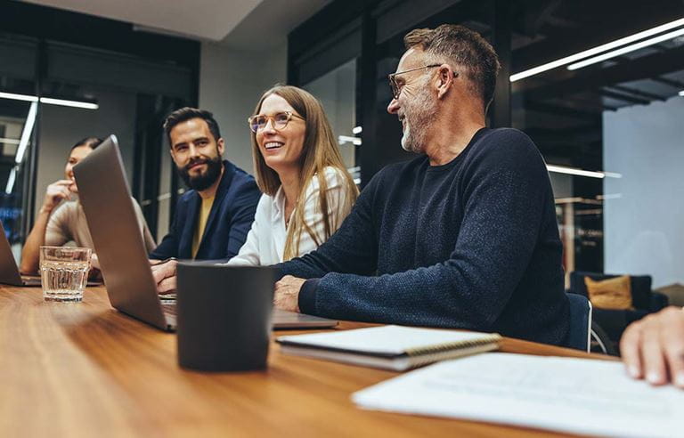 Business professionals in a meeting in a conference room smiling and talking.