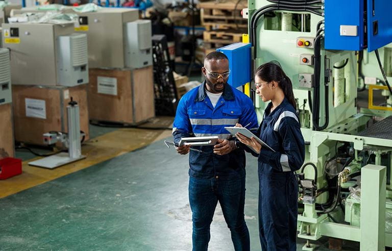 Two factory workers checking off a task list.