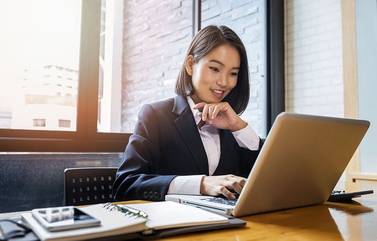 Business professional smiling while using their laptop computer.