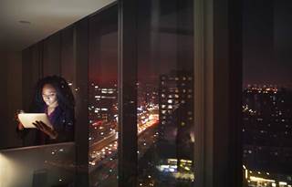 Business professional looking at tablet computer at nighttime.