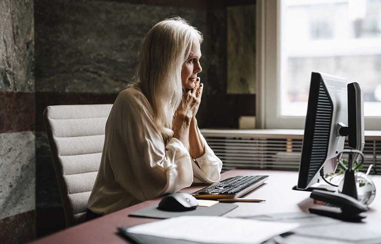 Business professional sitting at a desk looking at her computer monitor reading about Section 174 capitalization rules