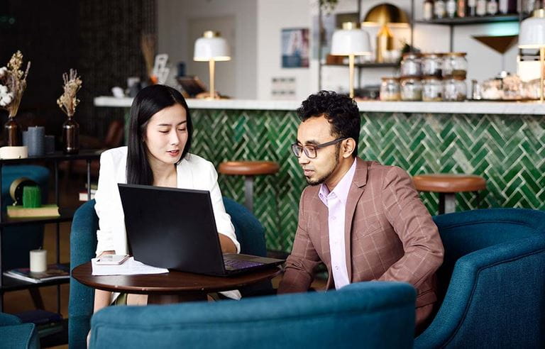 A financial advisor sitting with her client in a cafe discussing ways to avoid common investment mistakes.