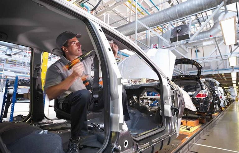 Automotive factory worker assembling an electrical vehicle.