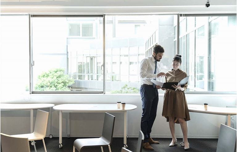 Two financial professionals in a modern office discussing how to mitigate risk.