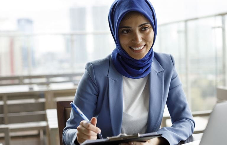 Business professional smiling while using a clipboard and taking notes