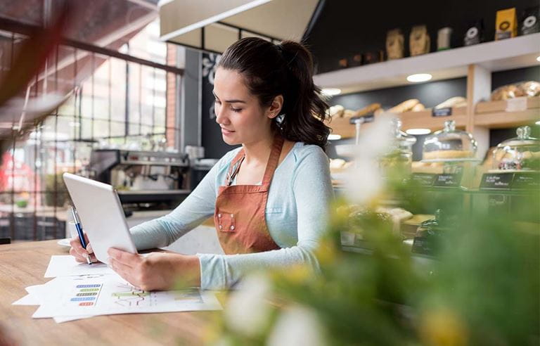 Franchisor using a tablet device with papers on the table underneath them