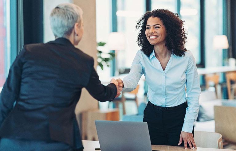 Two financial professionals smiling and greeting each other.