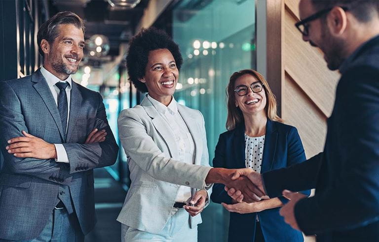 Employee benefits consultants shaking hands and smiling.