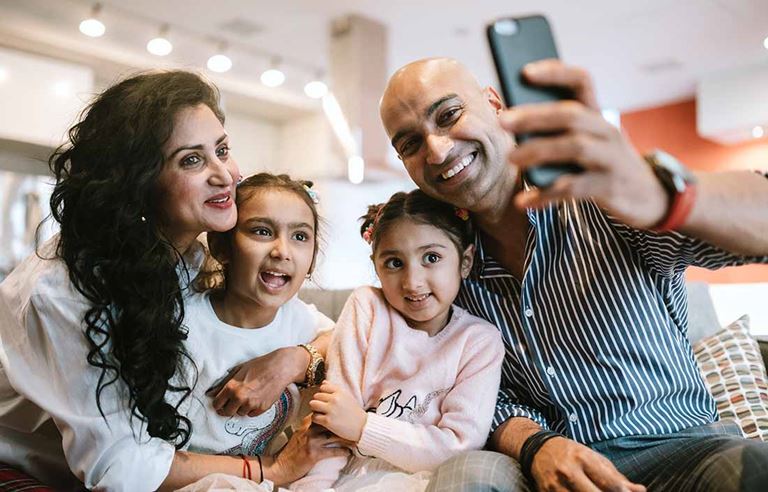 Parents and their children smiling and taking a selfie.