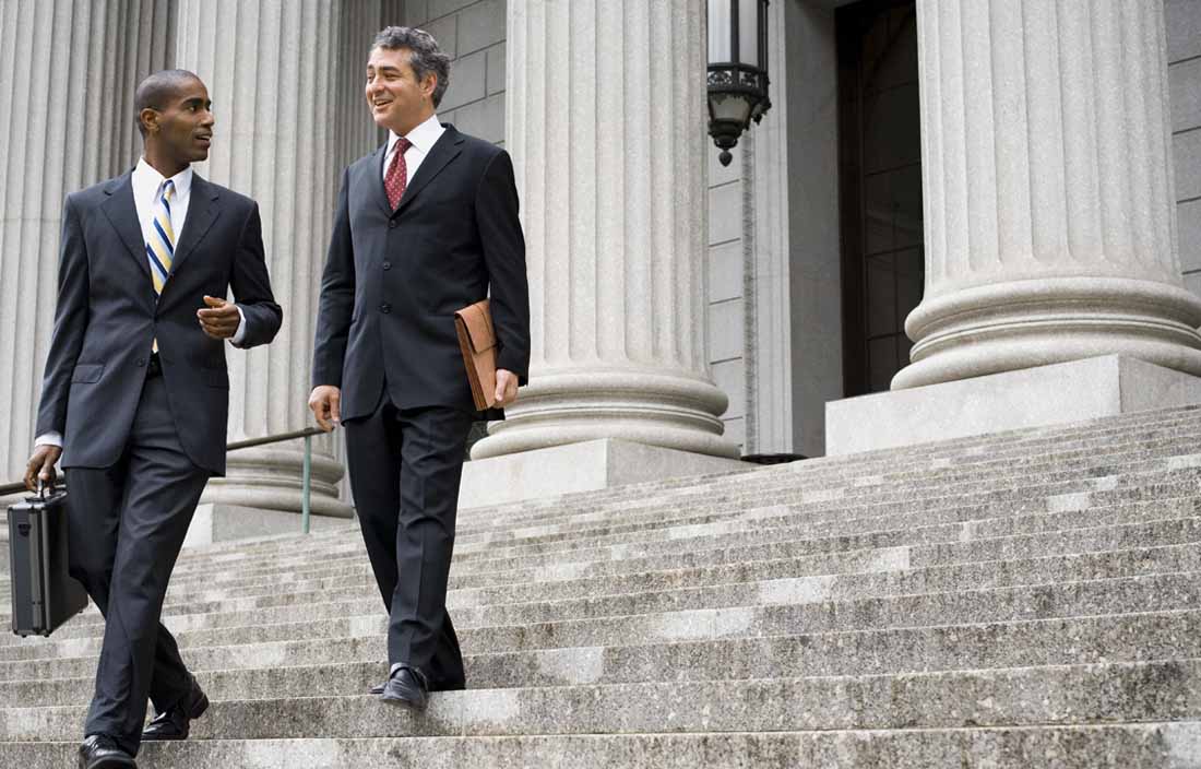 Two business professionals walking down steps of a government building.