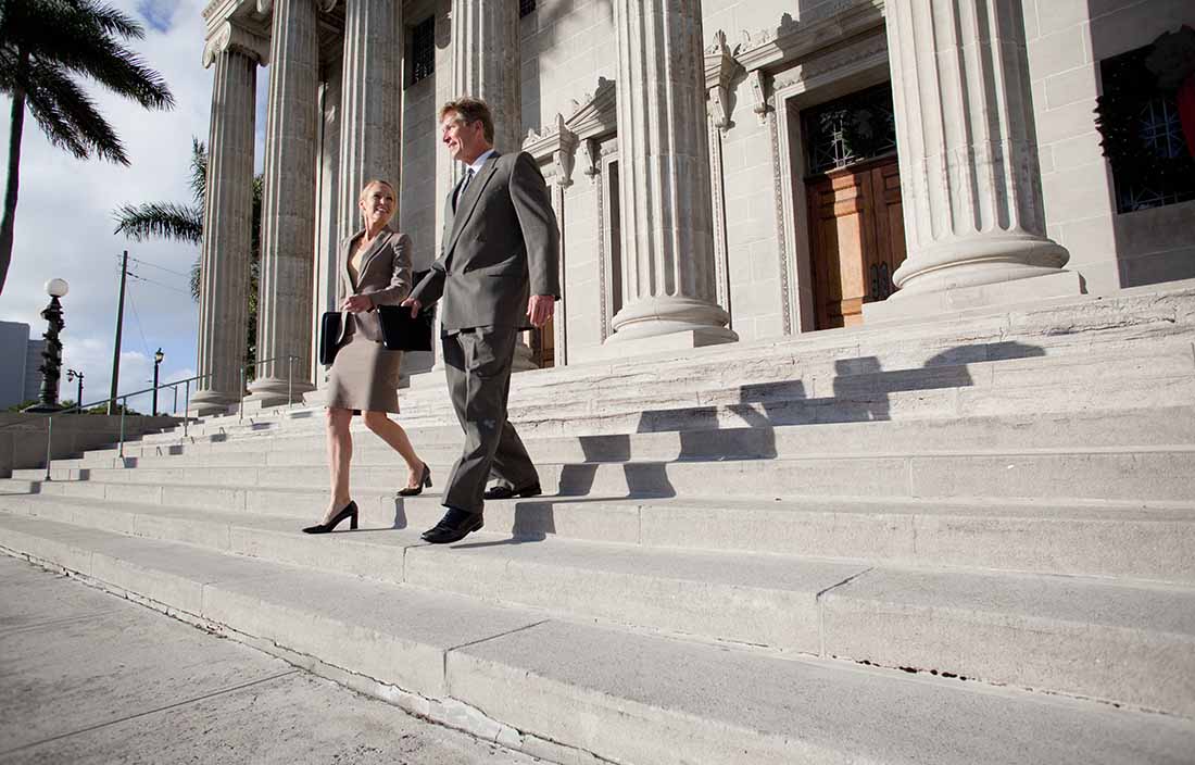 Two tax professionals walking down the steps of a government building.