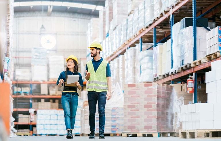 Factory workers walking through a warehouse.