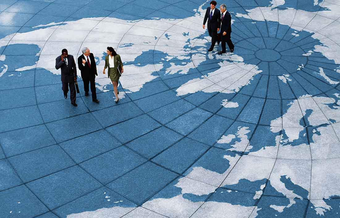 International business professionals walking across a world map.