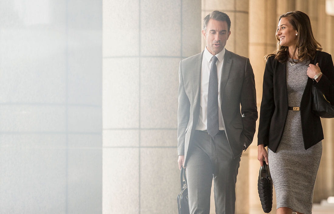 Two business professionals walking in a modern office and considering the outlook for individual tax laws.