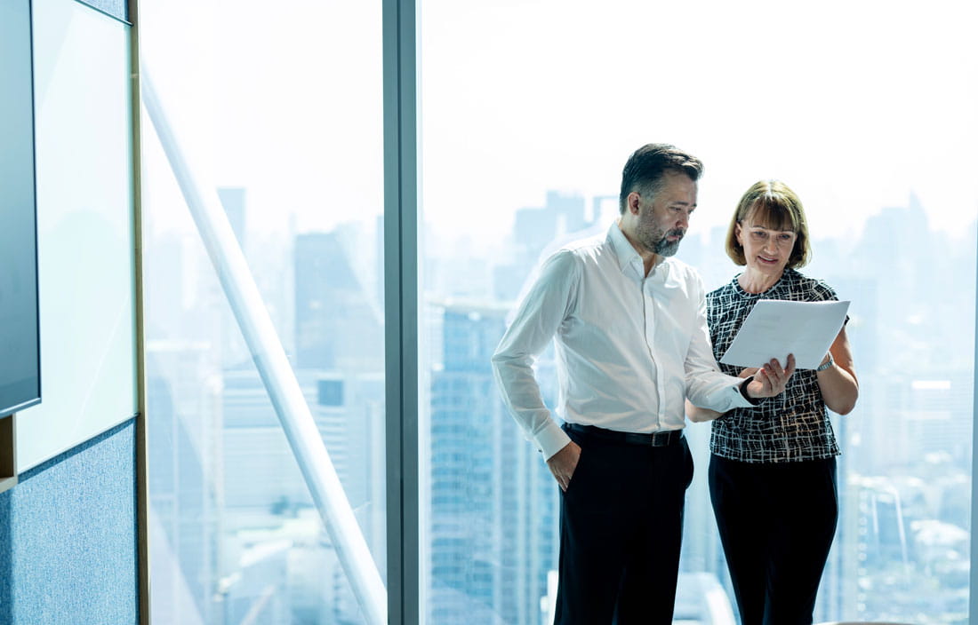 Two business professionals holding a notepad and discussing with one another