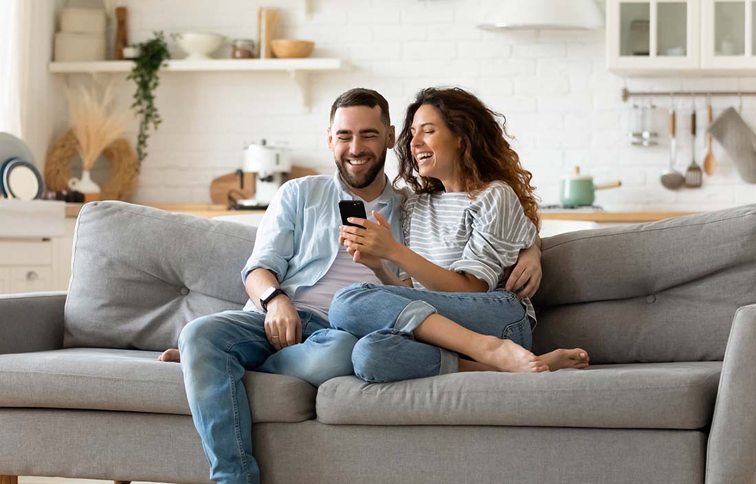 Happy couple sitting on their couch reviewing their financial goals for 2025.