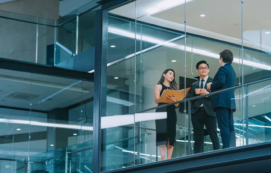 Financial professionals talking in a modern office hallway.