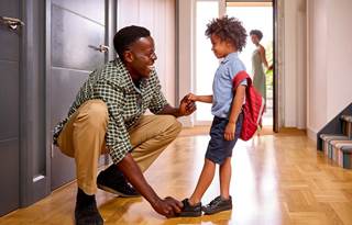 Parent smiling and helping their child get ready for school.