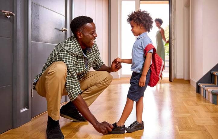 Parent smiling and helping their child get ready for school.