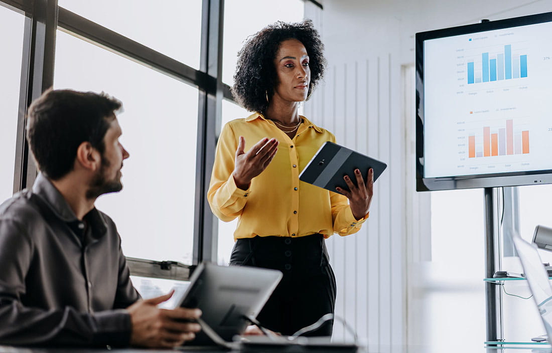 Business professional presenting to a group in a meeting.