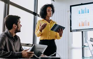 Business professional presenting to a group in a meeting.